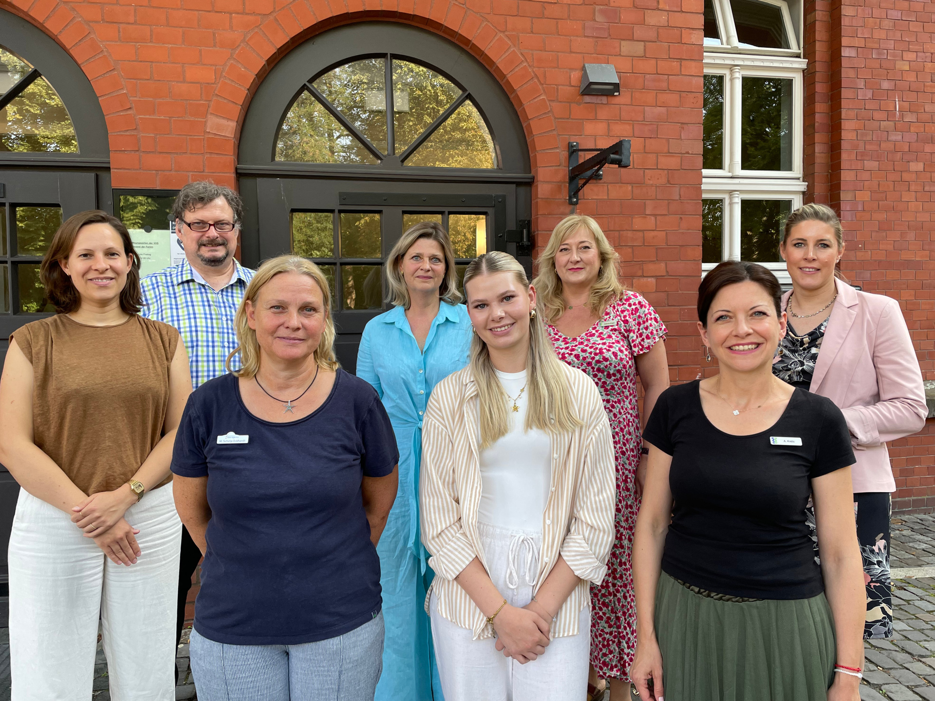 Personen stehen nebeneinaner vor dem Eingag der VHS Gütersloh.