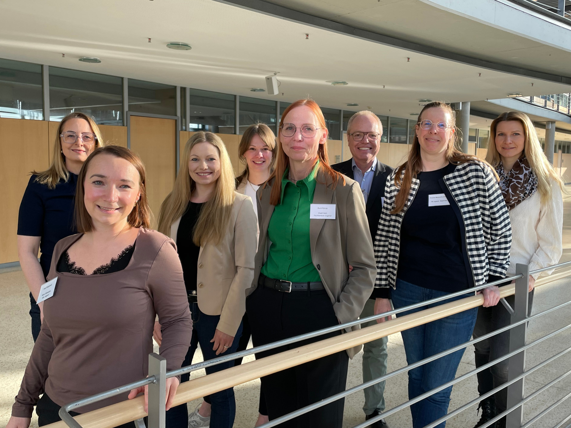 Personen stehen im Zickzack aufgereiht nebeneinander und schauen in die Kamera.