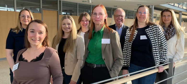 Personen stehen im Zickzack aufgereiht nebeneinander und schauen in die Kamera.