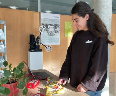 Person steht neben einem Computer und berührt die Früchte.