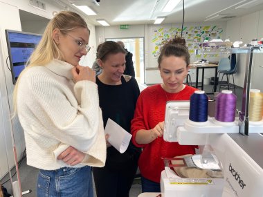 Personen stehen um die Stickmaschine herum.