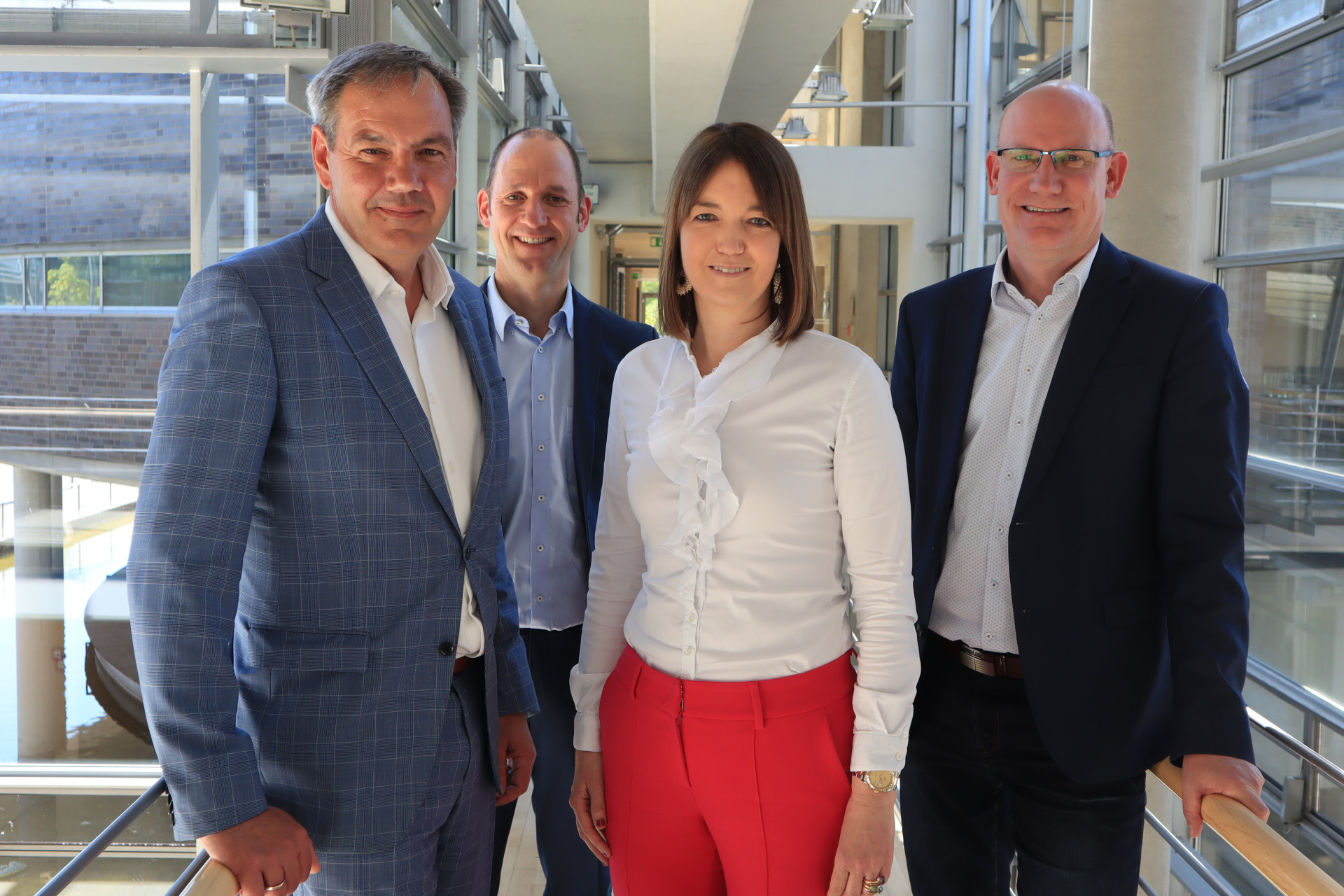 4 Personen, die im Kreishaus Gütersloh stehen und in die Kamera blicken. 