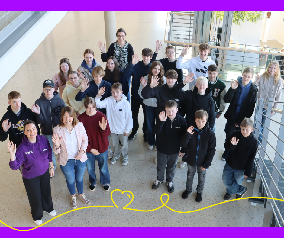 Ein Foto mit 23 Personen aus der Vogelperspektive im Foyer des Kreis Gütersloh. Der Großteil der Menschen sind Jugendliche. Im unteren Bereich ist eine Herzgrafik zu sehen.