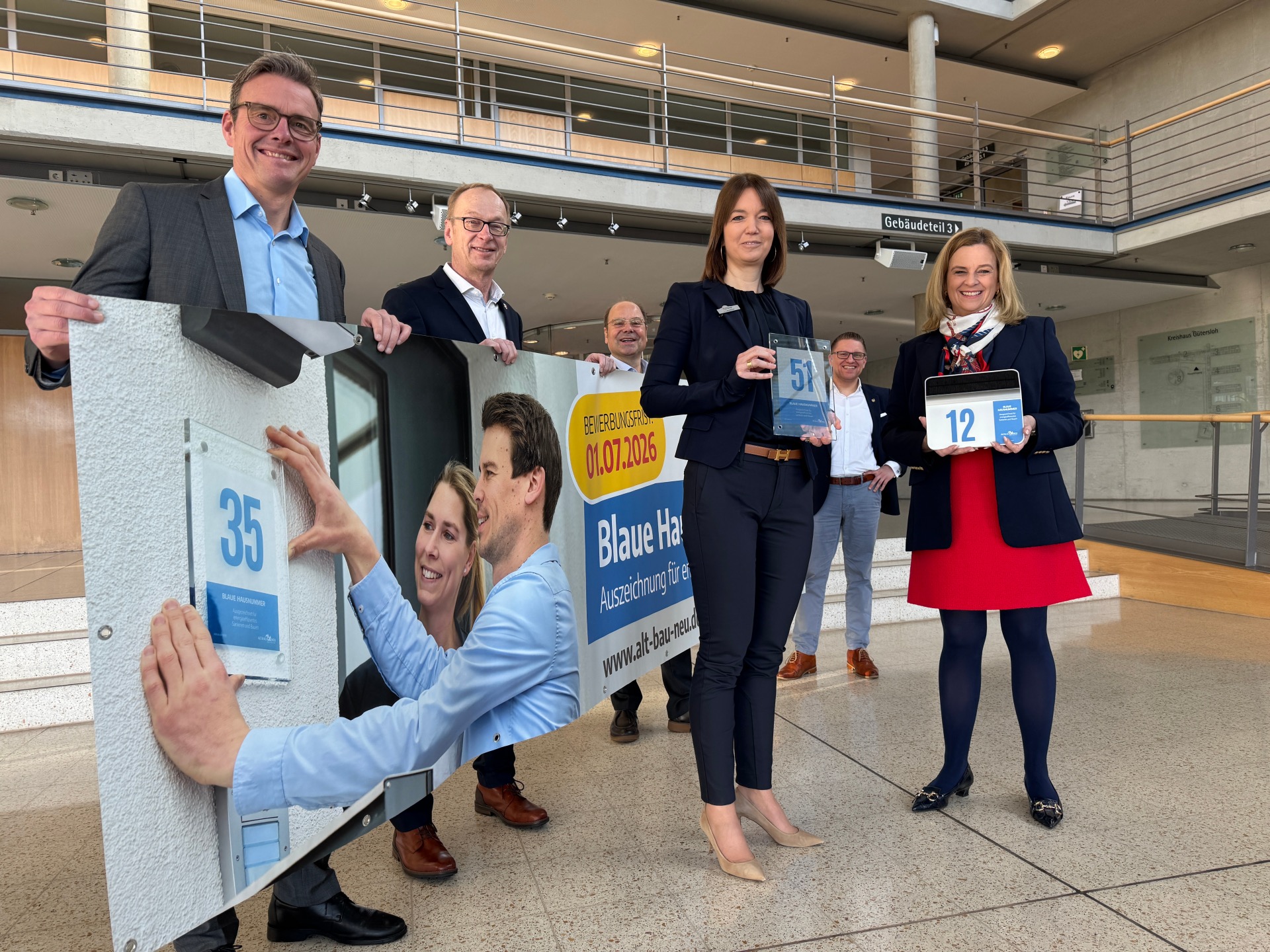 Personen stehen nebeneinander und halten einen Banner in den Händen.