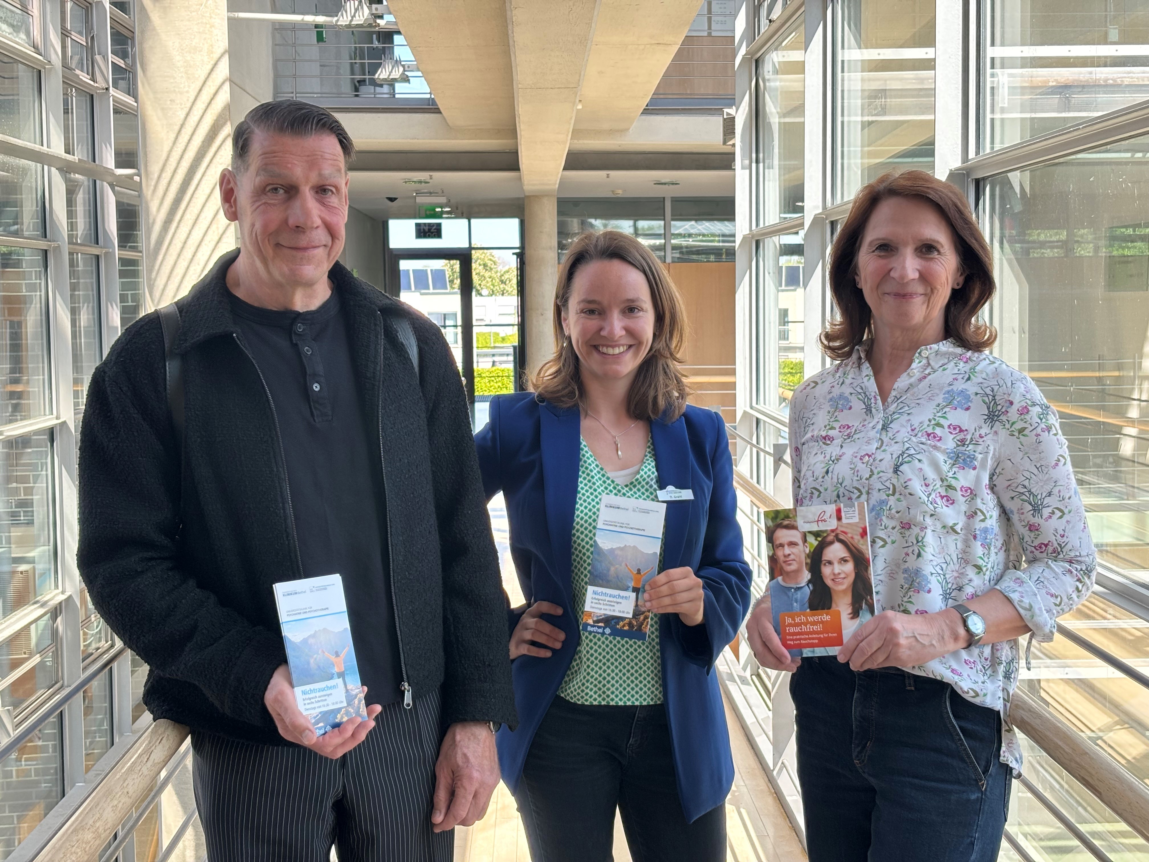 Drei Personen mit Flyern in der Hand