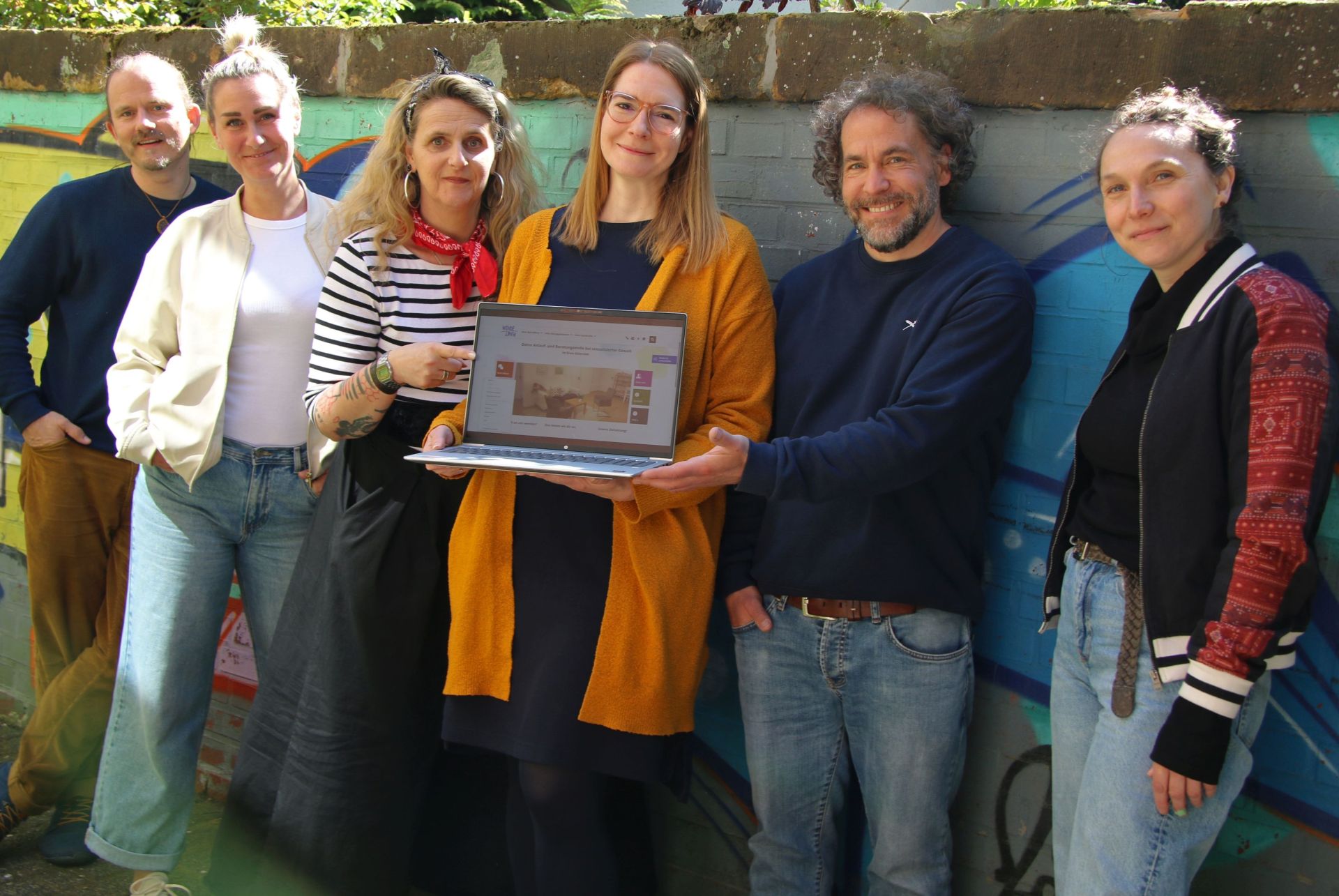 Das Team des Wendepunktes mit einem Laptop auf dem die Startseite der neuen Homepage zu sehen ist.