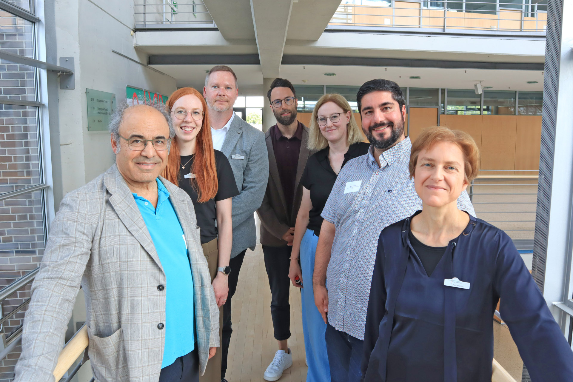 Personen stehen im Foyer des Kreishauses Gütersloh und blicken in die Kamera.