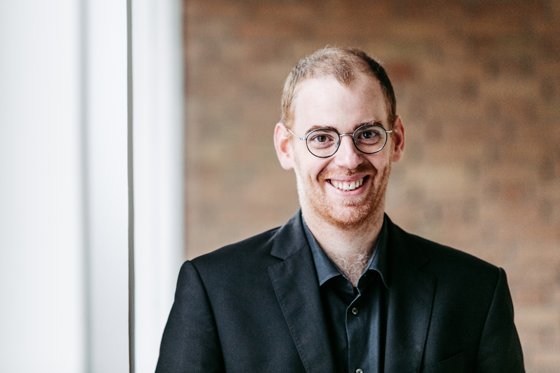 Ein Mann steht im Mittelpunkt und blickt in die Kamera.