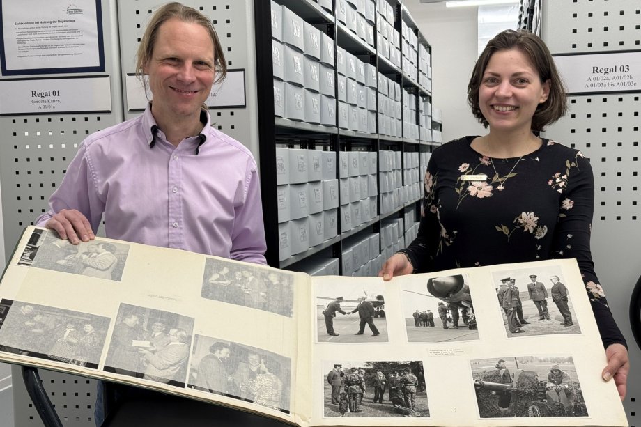 Julia Kuklik, Leiterin des Stadtarchivs, und Dr. Franz Jungbluth, Mitarbeiter des Kreisarchivs, präsentieren im magazinraum des Kreisarchivs ein Fotoalbum mit Schwarzweißaufnahmen der ehemals in Gütersloh stationierten britischen Streitkräfte. 
