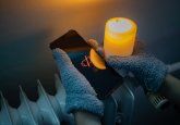 Cold Winter Blackout in Ukraine: Person in Gloves Holding Dead Phone and Candle near Cold Radiator Stromausfall