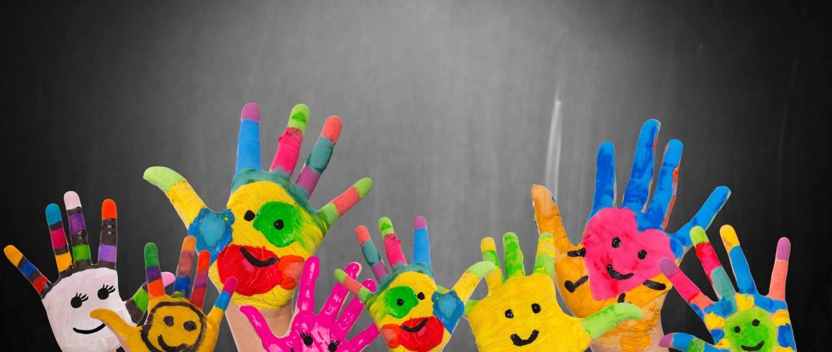 Bunte Kinderhände vor einer Schultafel