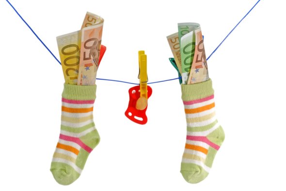 Socken mit Geld und ein Schnuller hängen an einer Wäscheleine
