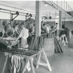 Schwarz-weiß Foto, das Arbeiter in einer Wurstküche zeigt.