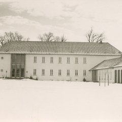 Schwarz-weiß-Foto: Funktionaler Schulbau mit schneebedecktem Dach
