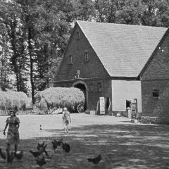 Schwarz-weiß-Foto: Zwei junge Frauen vor mehreren Bauernhofgebäuden
