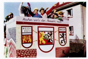 Farbfoto eines bemalten Wagens mit winkenden Menschen darauf.