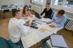 WorkshopKreisarchiv Eine Gruppe Jugendlicher sitzt um einem Tisch mit Akten und Computern