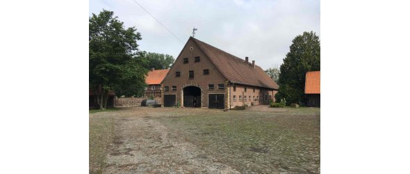 Das Bild zeigt das Haupthaus des Westhofs von Südost mit vorgelagertem Pflasterhof, Speicher links und Leibzucht rechts.