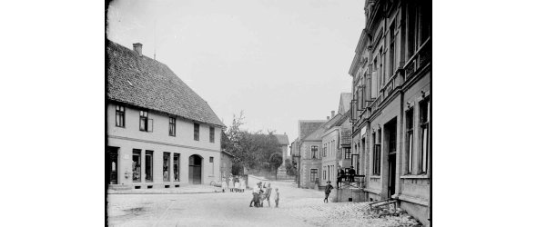 Das Bild zeigt mehrere Häuser der Freistraße in Borgholzhausen im Jahr 1915, links das sogenannte „Thorbecke-Haus“. In der Mitte des Bildes sind mehrere spielende Kinder zu sehen.