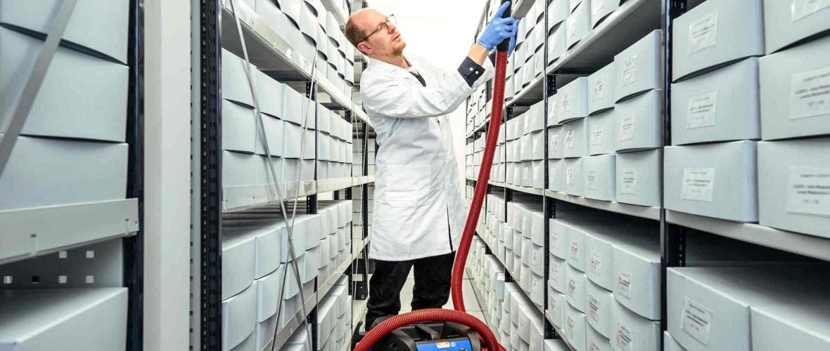 Archivmitarbeiter beim Reinigen des Magazins des Stadtarchivs Gütersloh.