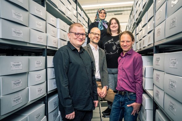 Gruppenbild zwischen zwei Regalen mit Archivkartons.
