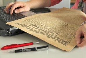 Benutzerin mit Notebook und historischer Zeitung