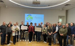 Personen stehen in einem Halbkreis, einige von ihnen halten Siegerurkunden in den Händen und blicken in die Kamera.